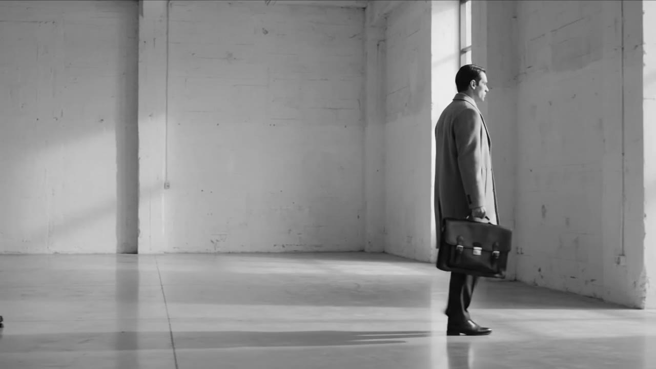 A man crossing a hall carrying the Hardy Briefcase
